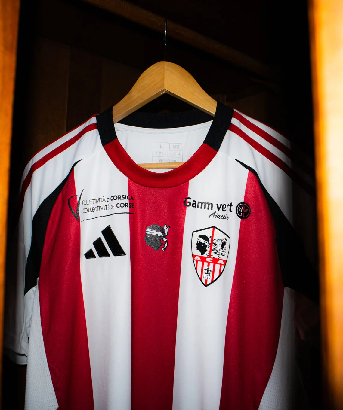 Le maillot de l'AC Ajaccio sur un cintre, l'écusson du club sur la poitrine